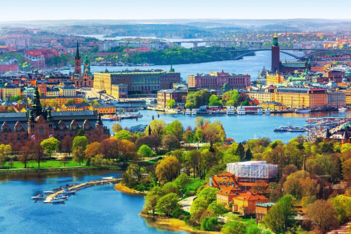 A town full of colorful buildings and green trees in sweden surrounded by water.