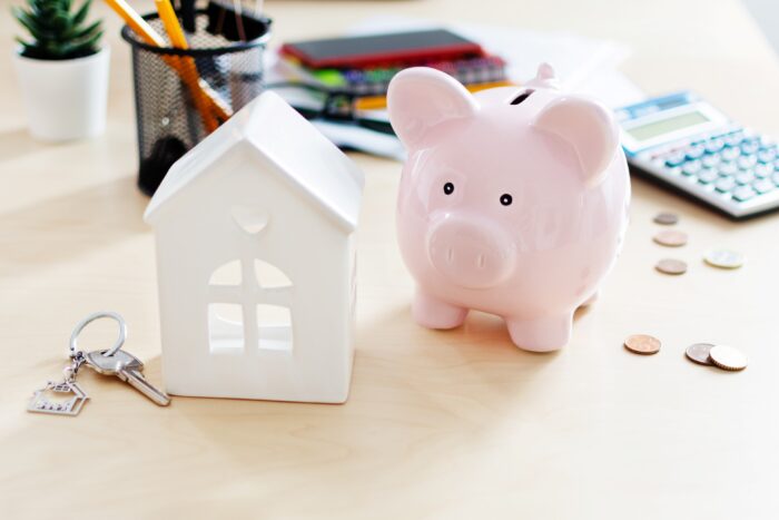 A piggy bank and a miniature house with a set of keys.