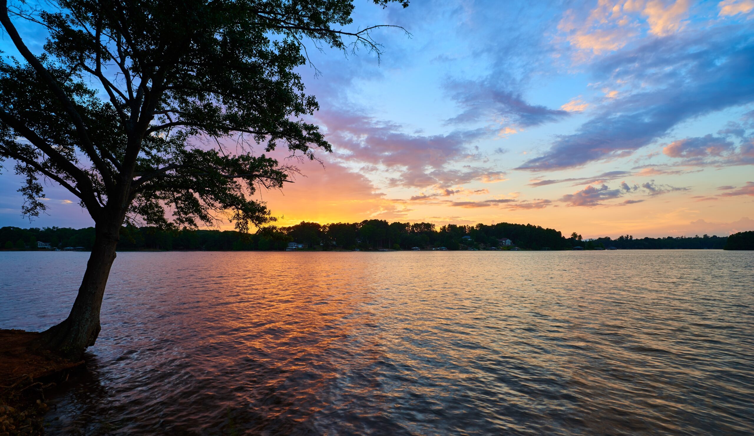 A lake at dusk with the colors of the setting sun reflected onto it.