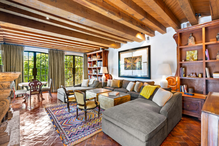 Living area with wood beams, terracotta flooring and a fireplace. 