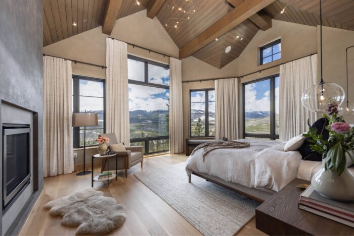 Primary suite in modern mountain estate with fireplace and views of snowcapped mountain peaks. 