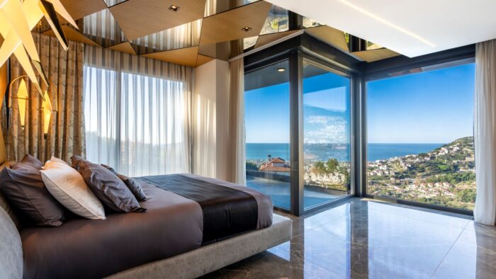 Villa bedroom with floor-to-ceiling windows and ocean views. 