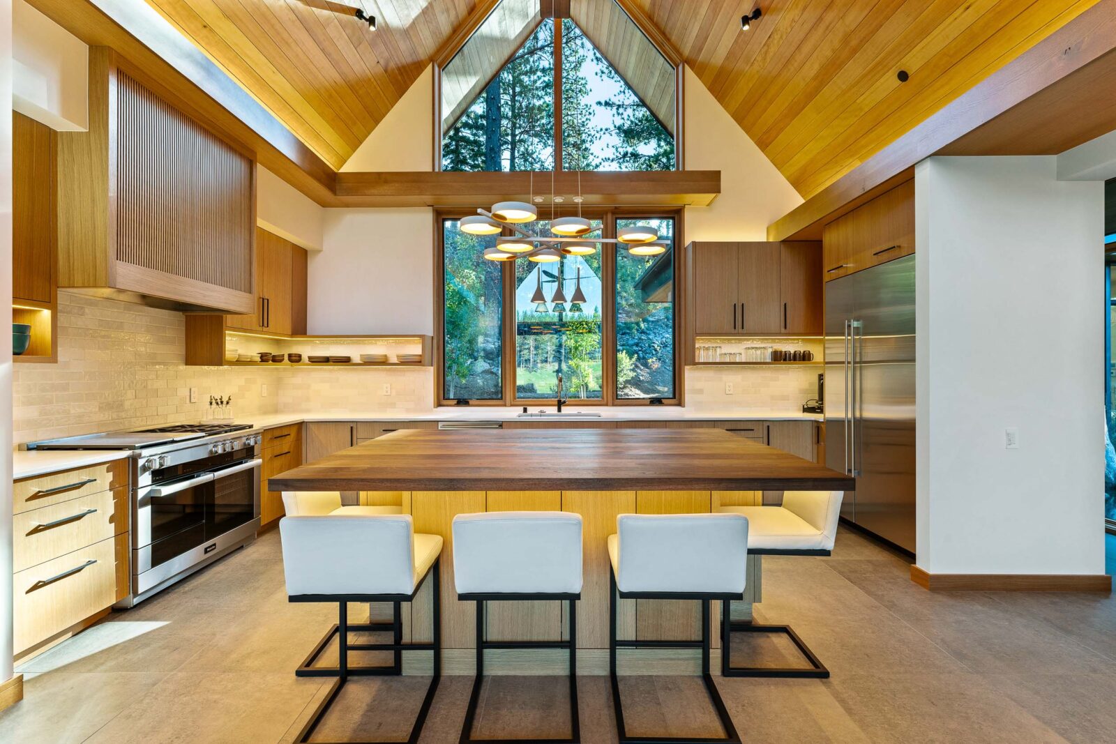 Sleek kitchen with wood accent, butcher-block center island and cathedral ceilings. 