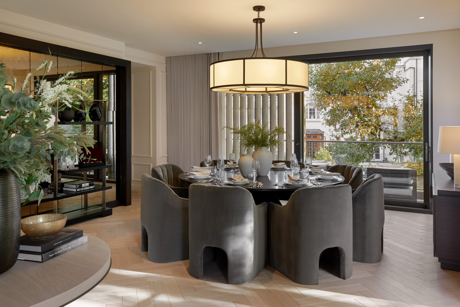 Dining room with round table and herringbone parquet floor in apartment overlooking London street